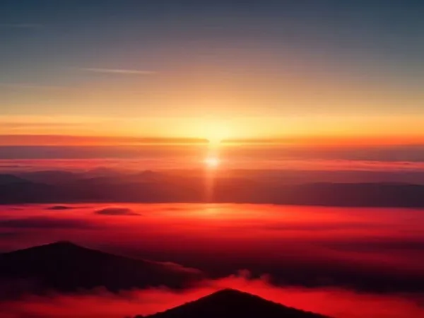 The sun rising above a sea of red-lit clouds seen from a mountain summit