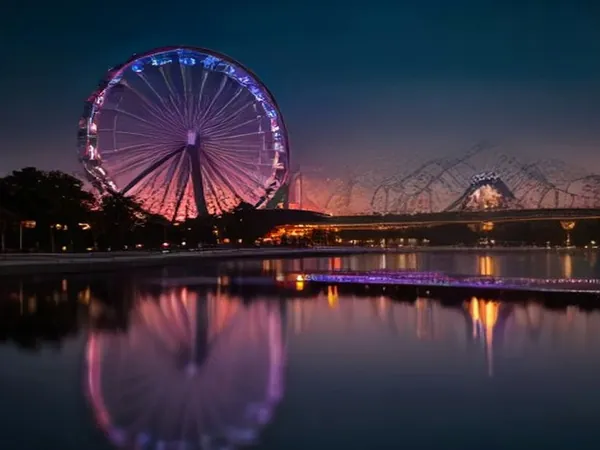 A lit Ferris wheel and roller coaster at dusk reflected in a lagoon