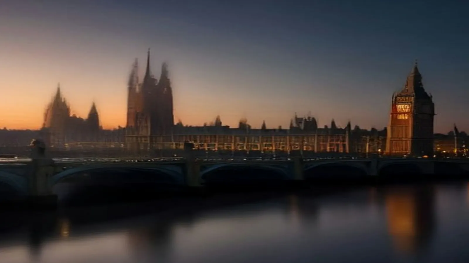The Houses of Parliament and its clock tower lit gold at dusk beyond Westminster Bridge and the River Thames