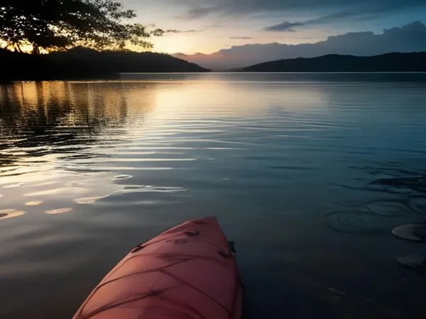 The bow of a kayak on a calm bay at dusk